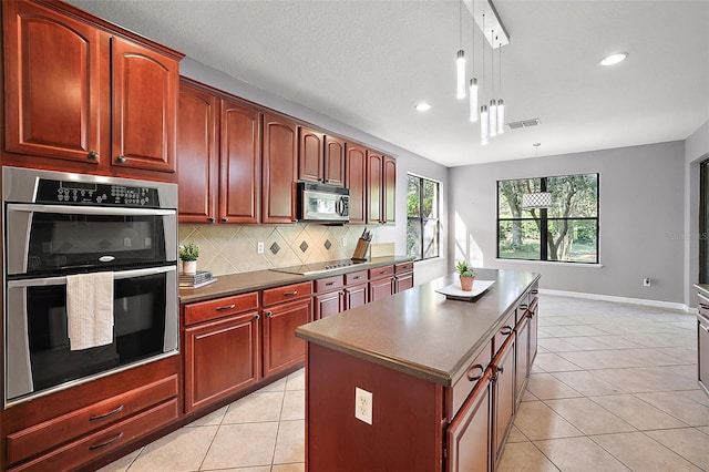 kitchen featuring backsplash, a kitchen island, decorative light fixtures, and appliances with stainless steel finishes