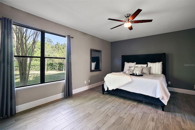 bedroom featuring multiple windows, ceiling fan, and light hardwood / wood-style flooring