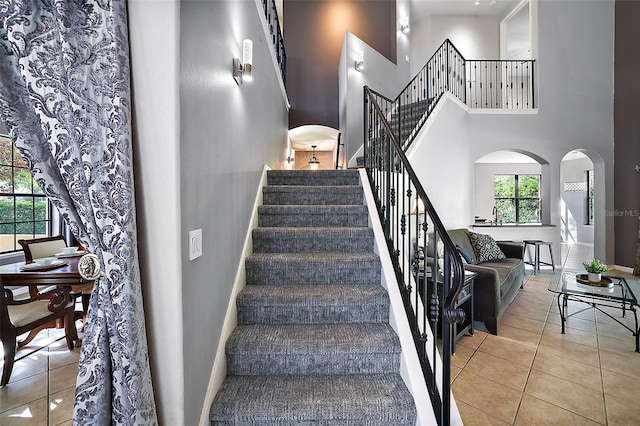 staircase featuring tile patterned floors and a towering ceiling