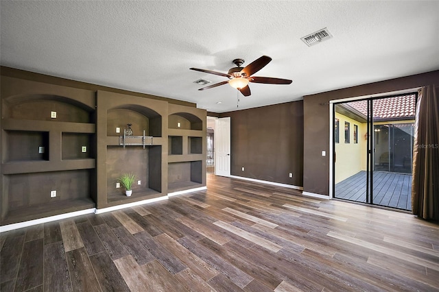 unfurnished living room with hardwood / wood-style floors, ceiling fan, a textured ceiling, and built in shelves