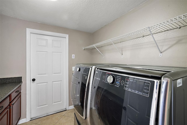 laundry area featuring light tile patterned flooring, washing machine and dryer, and a textured ceiling