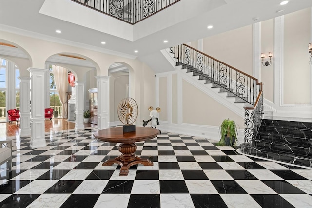 interior space featuring ornamental molding, a high ceiling, light tile floors, and decorative columns