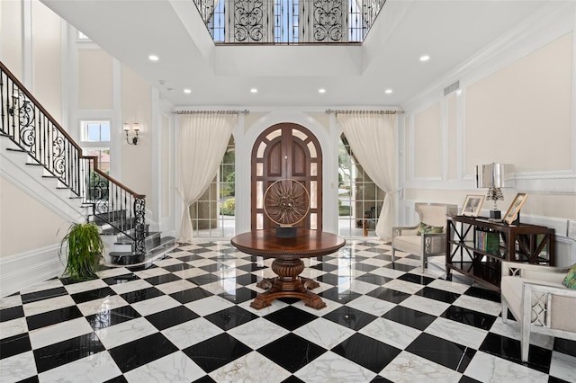 tiled entryway featuring a wealth of natural light, crown molding, and a high ceiling