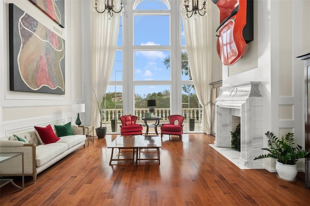 living room featuring an inviting chandelier, dark hardwood / wood-style flooring, and a premium fireplace