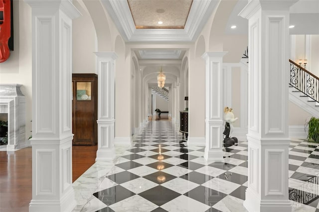 foyer with a tray ceiling, decorative columns, crown molding, and dark tile floors