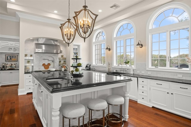 kitchen featuring dark hardwood / wood-style flooring, a center island with sink, tasteful backsplash, and a chandelier