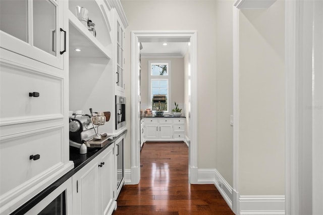 hall with dark wood-type flooring and crown molding