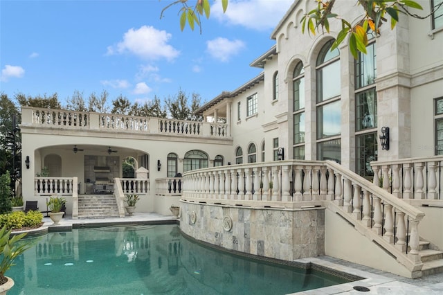 rear view of property featuring ceiling fan and a balcony