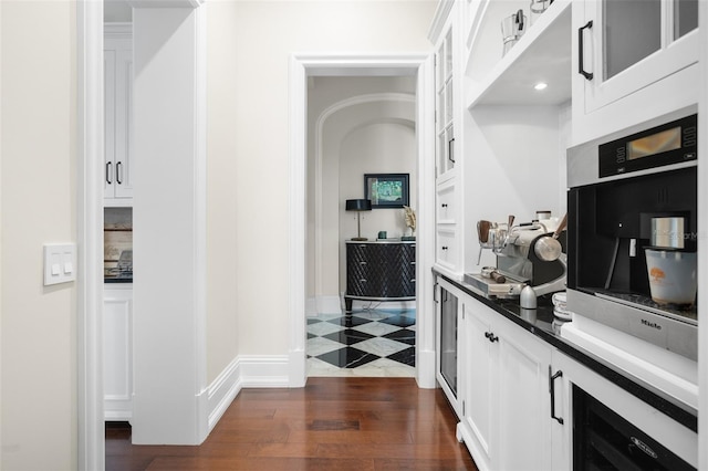 interior space featuring beverage cooler, dark tile flooring, white cabinetry, and stainless steel oven