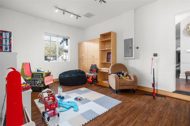 rec room with dark hardwood / wood-style floors and track lighting