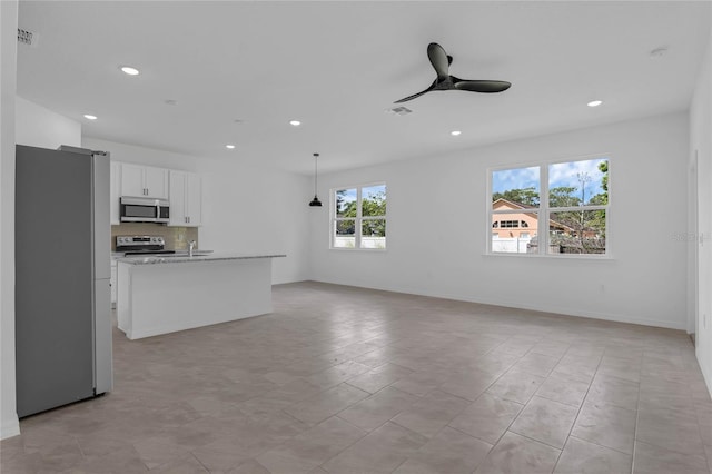 kitchen with hanging light fixtures, light stone countertops, stainless steel appliances, white cabinetry, and ceiling fan