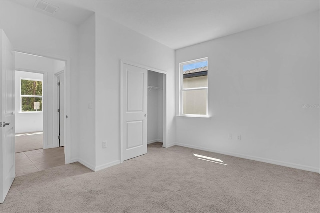 unfurnished bedroom featuring a closet and light colored carpet