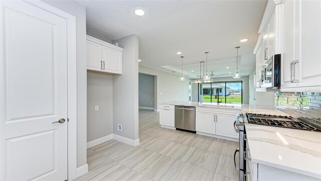 kitchen with white cabinets, stainless steel appliances, light stone counters, and hanging light fixtures