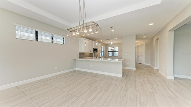 kitchen featuring kitchen peninsula, decorative backsplash, white cabinets, and pendant lighting