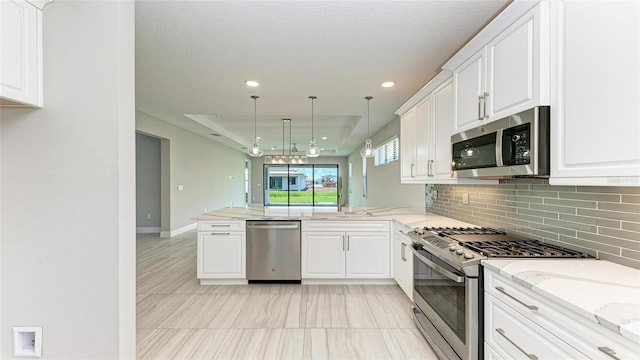 kitchen featuring white cabinetry, hanging light fixtures, kitchen peninsula, stainless steel appliances, and backsplash