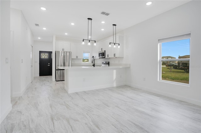 kitchen featuring sink, kitchen peninsula, hanging light fixtures, white cabinetry, and stainless steel appliances