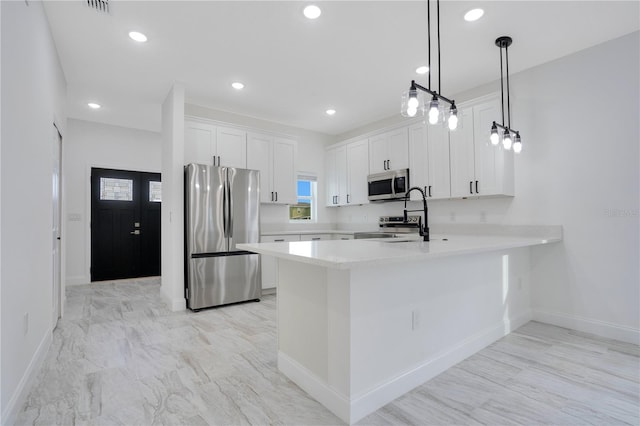 kitchen with appliances with stainless steel finishes, kitchen peninsula, white cabinetry, and pendant lighting