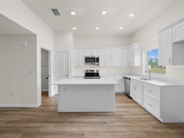 kitchen featuring a center island, sink, light hardwood / wood-style floors, white cabinetry, and stainless steel appliances