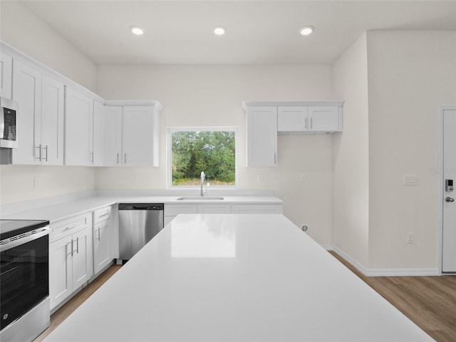 kitchen with hardwood / wood-style floors, sink, white cabinetry, and stainless steel appliances