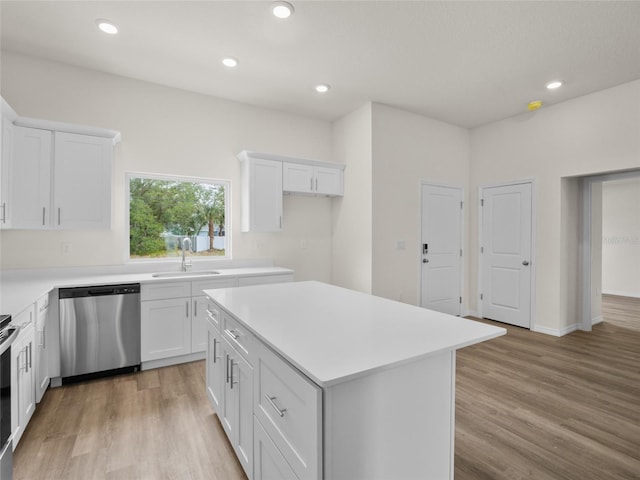 kitchen featuring stainless steel appliances, a kitchen island, sink, light hardwood / wood-style floors, and white cabinetry