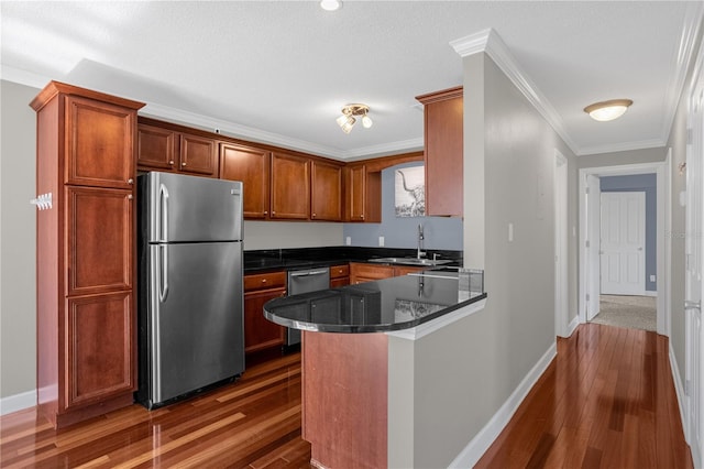 kitchen featuring appliances with stainless steel finishes, crown molding, kitchen peninsula, and dark hardwood / wood-style flooring