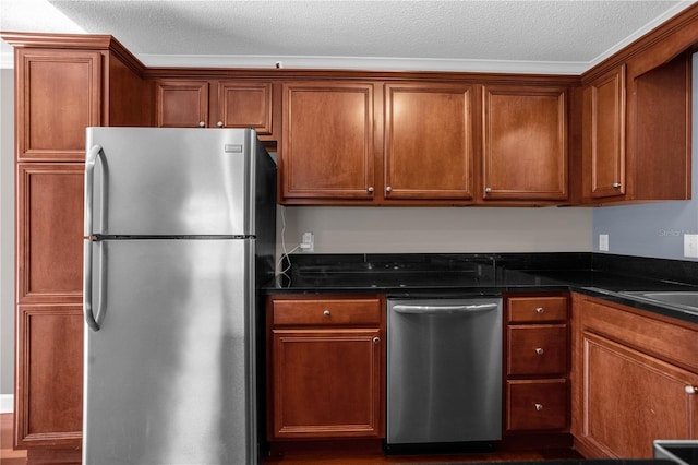 kitchen with a textured ceiling, appliances with stainless steel finishes, dark hardwood / wood-style flooring, and dark stone counters