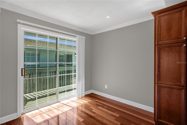 empty room featuring ornamental molding, light hardwood / wood-style flooring, and a textured ceiling