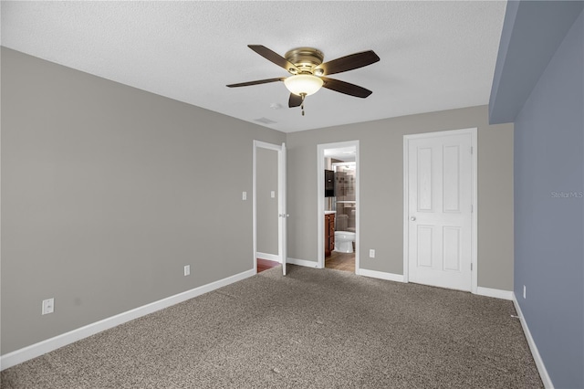 unfurnished bedroom with a closet, connected bathroom, dark colored carpet, and ceiling fan