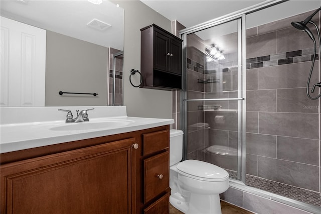 bathroom with vanity, a shower with door, and toilet