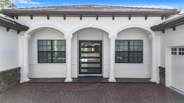 property entrance with a garage and stucco siding