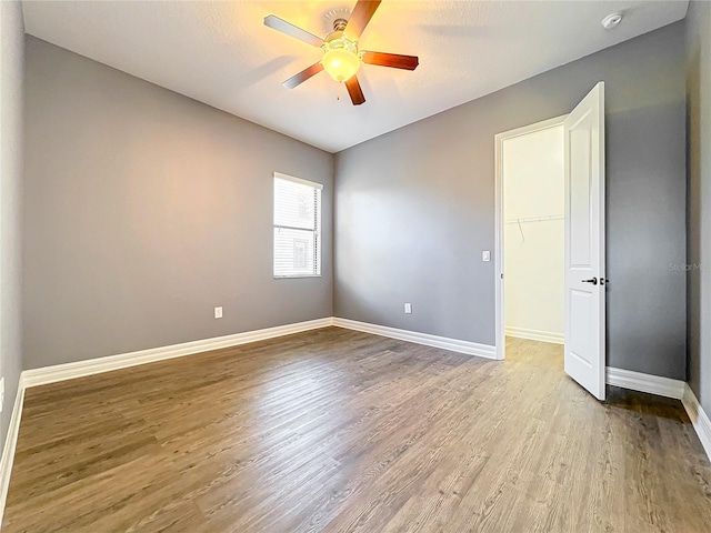 spare room featuring a ceiling fan, baseboards, and wood finished floors