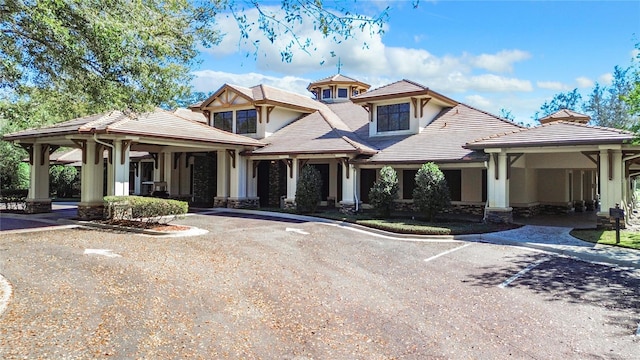 view of front facade featuring stone siding, a tile roof, driveway, and stucco siding