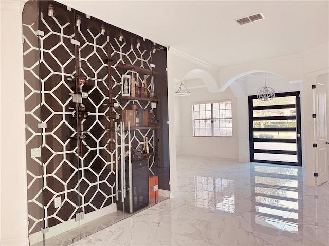 interior space with arched walkways, a notable chandelier, visible vents, marble finish floor, and ornamental molding