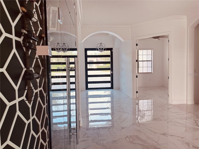 interior space featuring arched walkways, marble finish floor, a chandelier, and a wealth of natural light