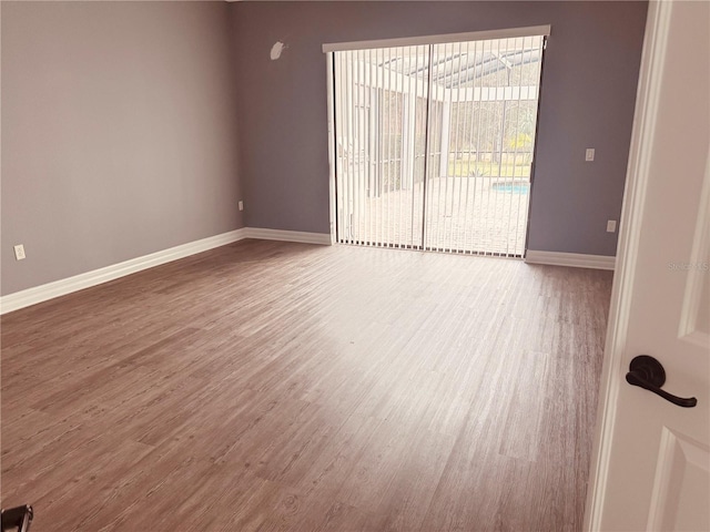 spare room with baseboards and wood finished floors