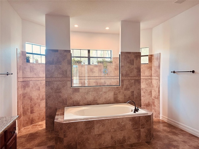 bathroom featuring baseboards, walk in shower, a bath, and vanity