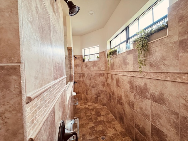 bathroom featuring tile walls and a tile shower