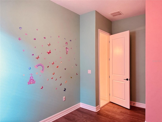 unfurnished bedroom featuring wood finished floors, visible vents, and baseboards