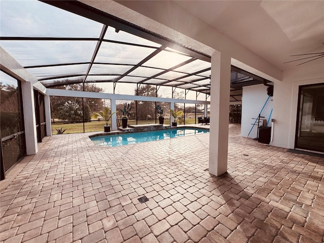 view of swimming pool with ceiling fan, a patio area, and glass enclosure