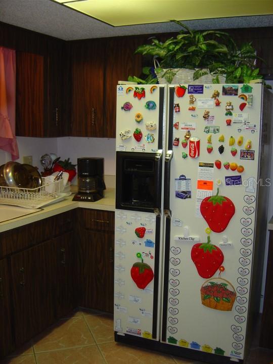 kitchen with dark brown cabinets, fridge, light tile floors, and sink