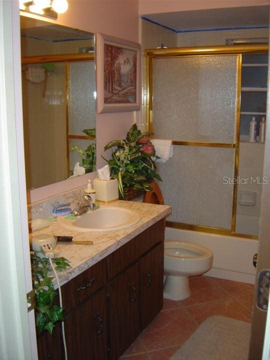 full bathroom with enclosed tub / shower combo, toilet, tile floors, and vanity