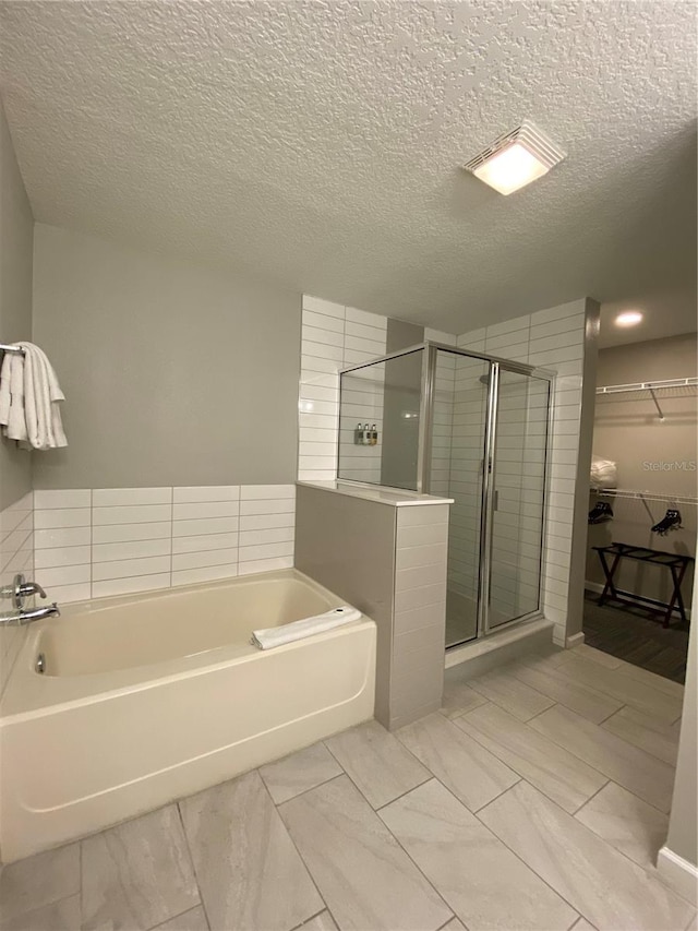 bathroom with a textured ceiling, independent shower and bath, and tile flooring