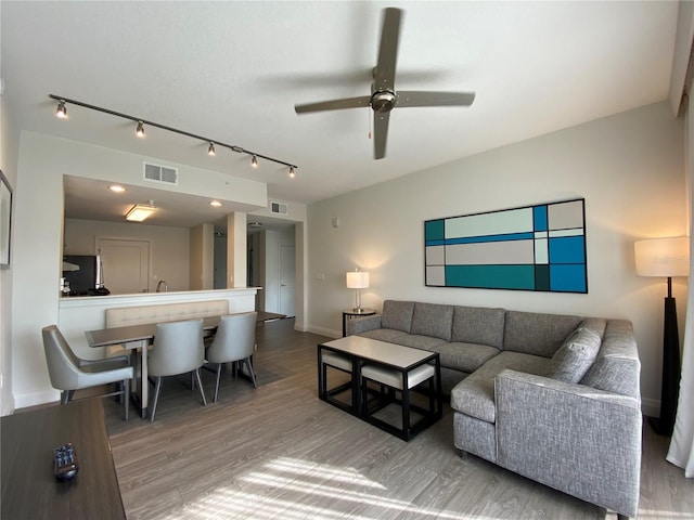 living room featuring rail lighting, wood-type flooring, and ceiling fan