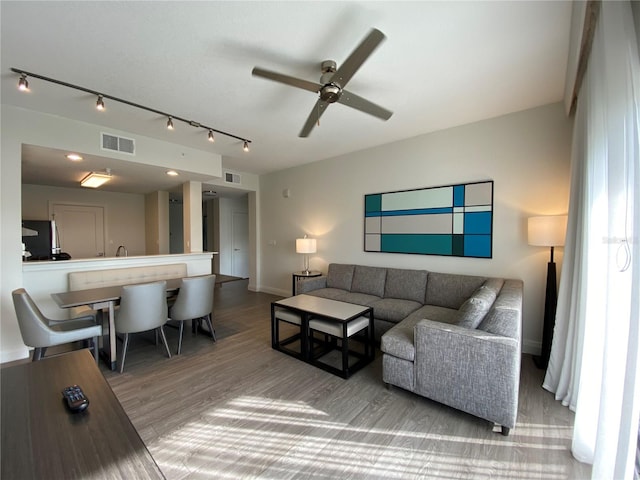 living room with rail lighting, wood-type flooring, and ceiling fan