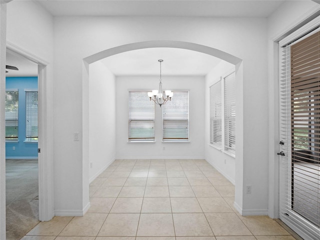 unfurnished dining area with light tile patterned flooring and a notable chandelier