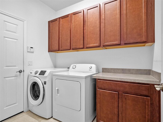 laundry area featuring light tile patterned flooring, cabinets, and independent washer and dryer