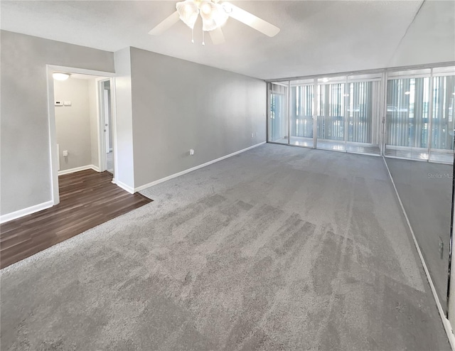 carpeted spare room featuring floor to ceiling windows and ceiling fan