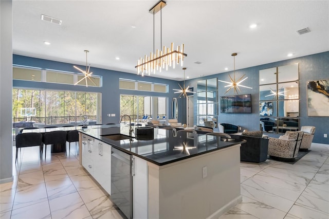 kitchen featuring dishwasher, white cabinets, a spacious island, sink, and hanging light fixtures