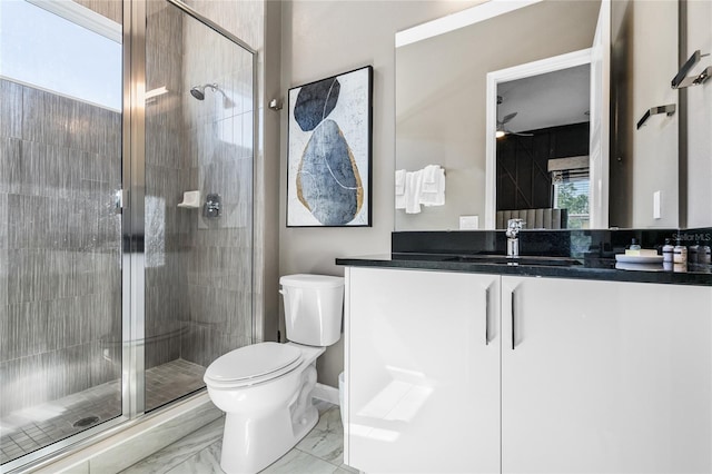 bathroom featuring vanity, ceiling fan, toilet, and a shower with shower door