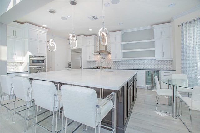 kitchen with decorative light fixtures, white cabinetry, backsplash, appliances with stainless steel finishes, and a breakfast bar area